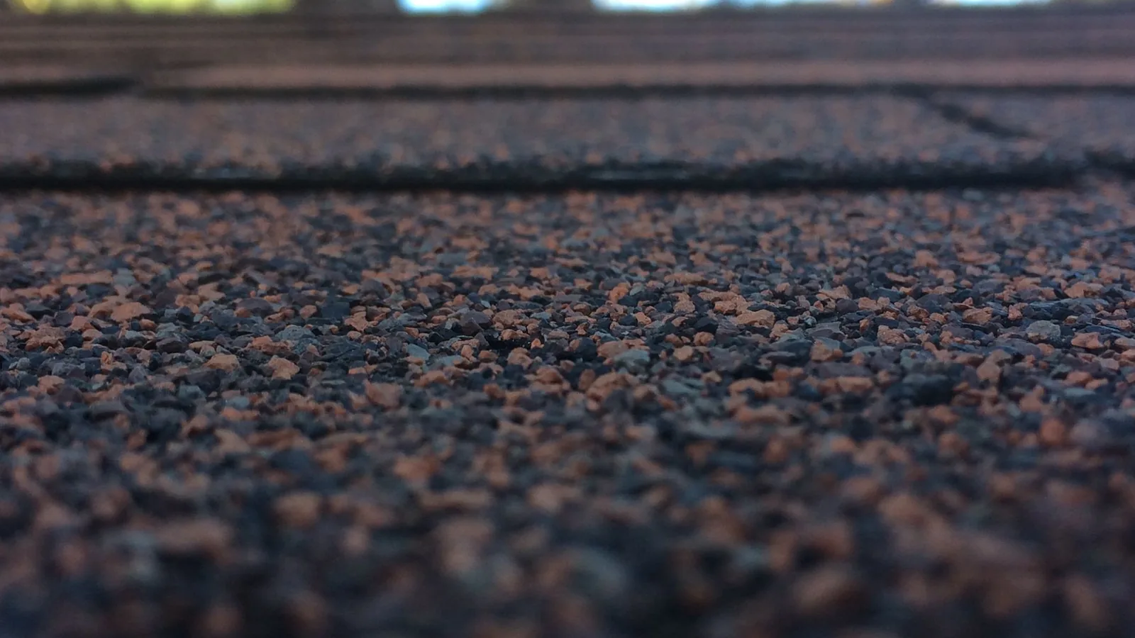 Close view across an asphalt shingle surface with granules and layered edges visible