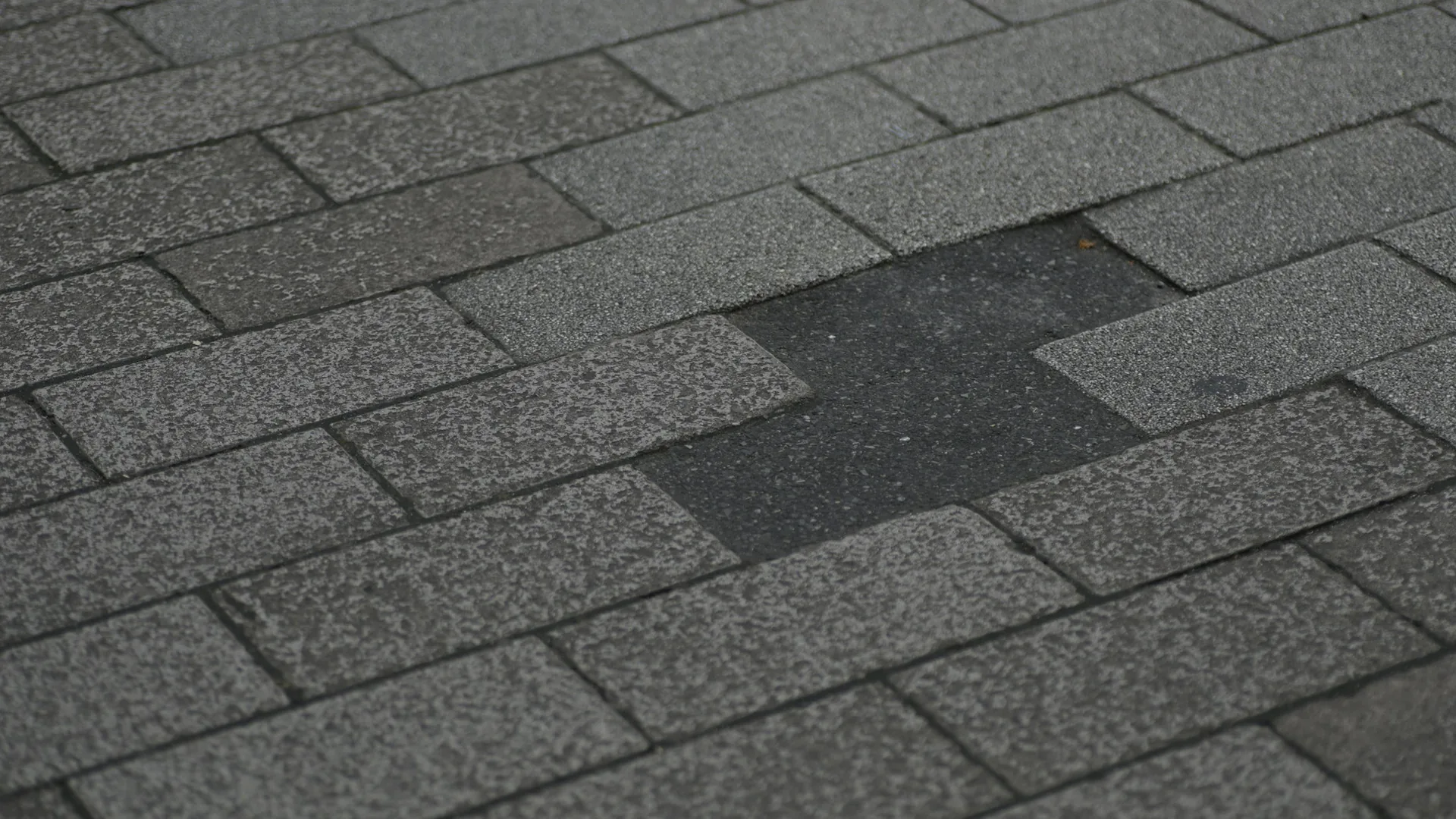 Close view of an asphalt roof with several missing shingle tabs and exposed material below