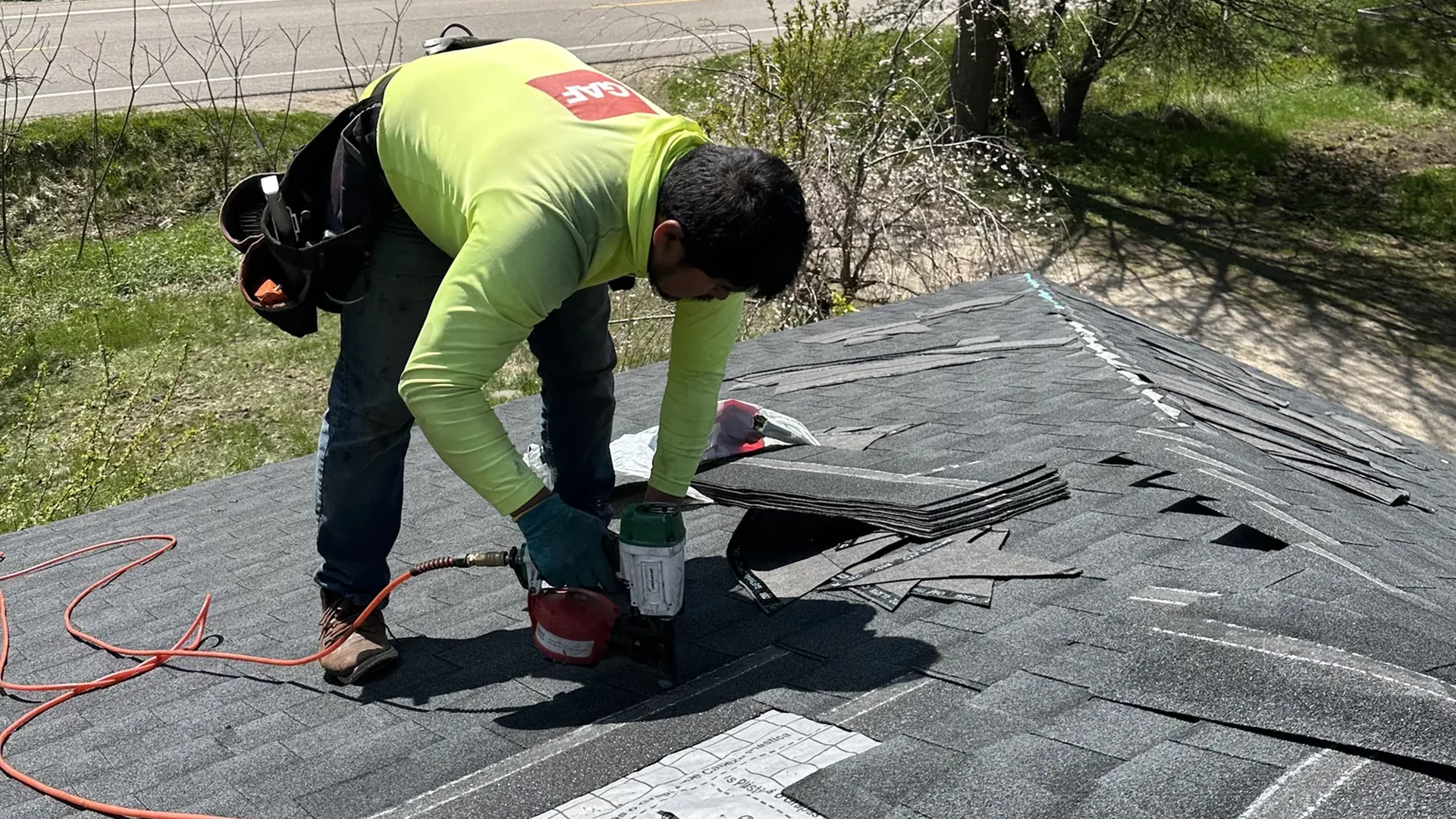 GAF-branded Platinum Roofing installer fastening asphalt shingles on a West Michigan home